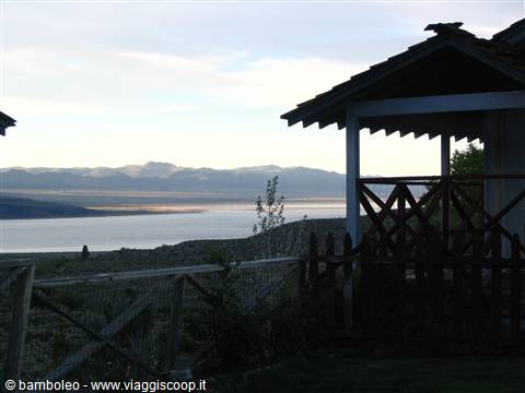 Wooden porch in shade overlooking a silvery lake and distant mountains