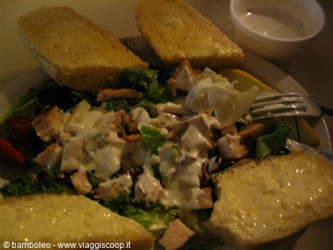 Caesar salad with chicken, creamy dressing and buttered bread slices