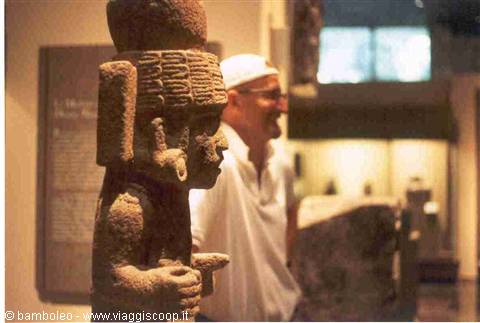 Smiling visitor beside a stone statue inside a museum