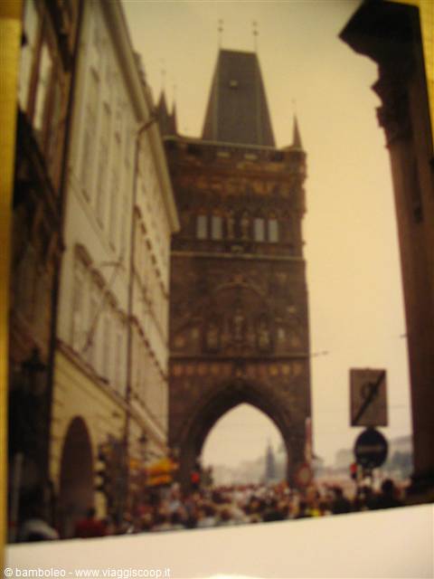 Crowds of tourists under Prague's Gothic Powder Tower, dark stone