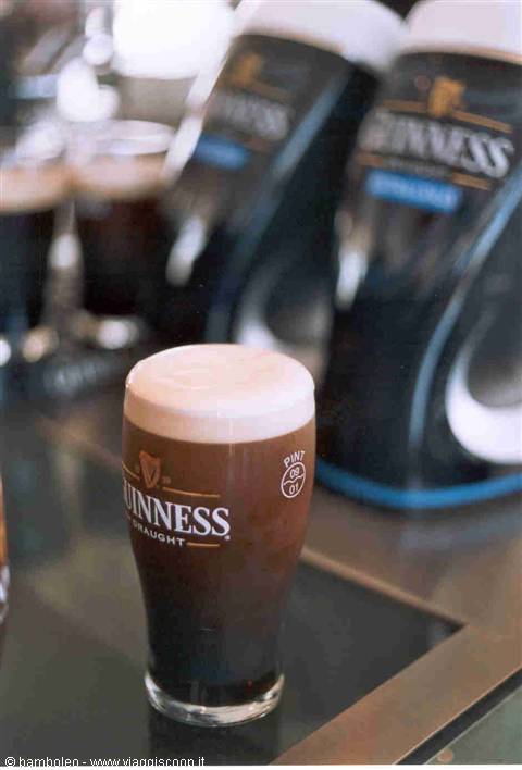 Pint of Guinness with white foam on the bar counter, taps in background