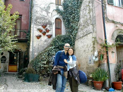 Couple hugging in a stone alley covered with ivy and flower pots