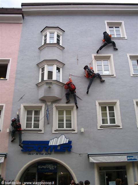 Climbers roped on the gray facade of the Sportler store