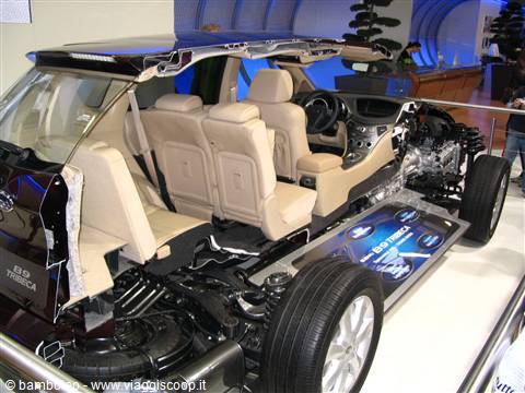 Cutaway car showing beige seats and exposed engine at auto show