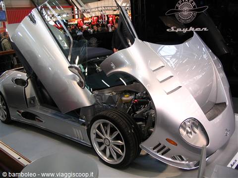 Silver Spyker sports car with open doors displayed at a motor show