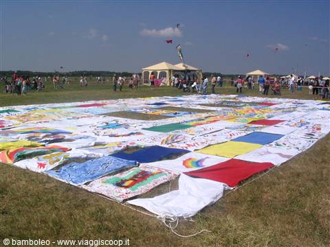 Giant kite made of colorful painted panels laid out on grass at festival