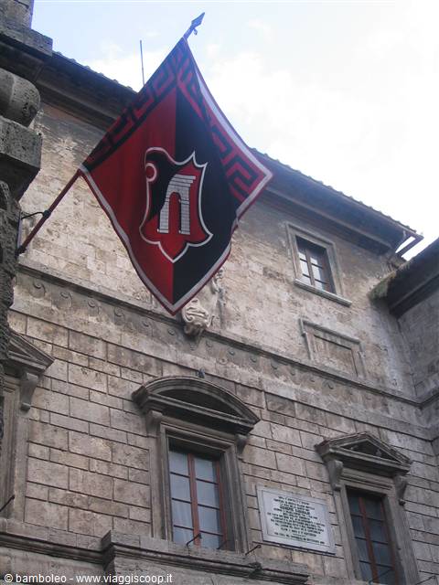 Red and black eagle flag on a medieval stone building in Pitigliano