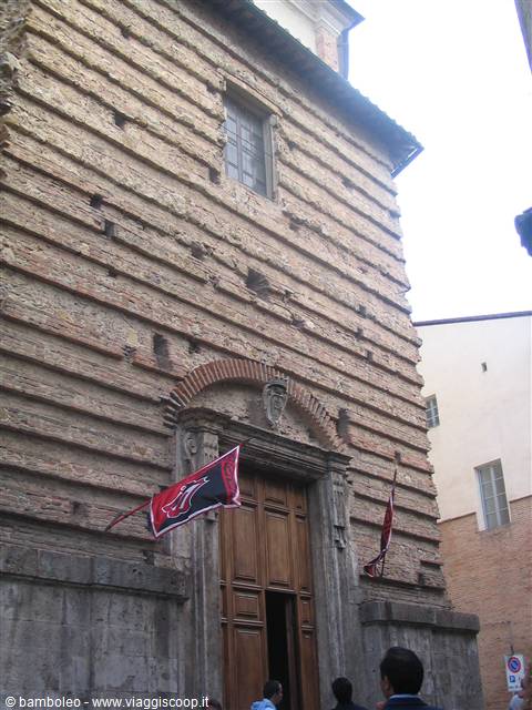 Brick church facade in Siena with Contrada flags above the wooden portal