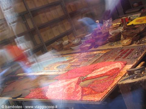 Artisan workshop: red mosaic with female figure on table, wooden shelves