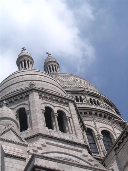 The white domes of Sacré-Cœur in Paris against a cloudy sky