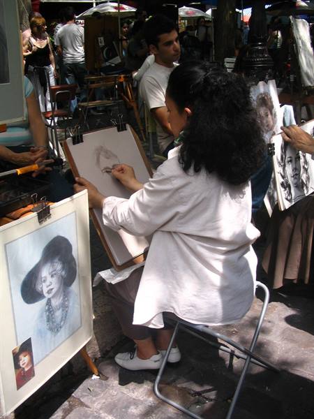 Portrait artist sketching pastel portraits at San Telmo outdoor market