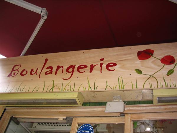 Painted wooden sign with red poppies above a boulangerie
