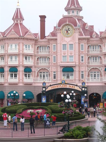 Disneyland Park entrance with the pink hotel, tourists among flower gardens