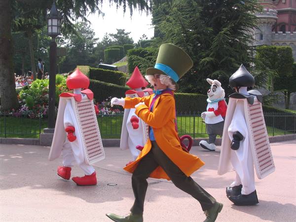 The Mad Hatter parades with playing cards and White Rabbit at Disneyland