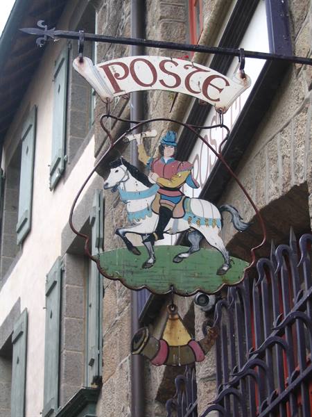 Metal Poste sign with painted rider on white horse hanging from stone facade