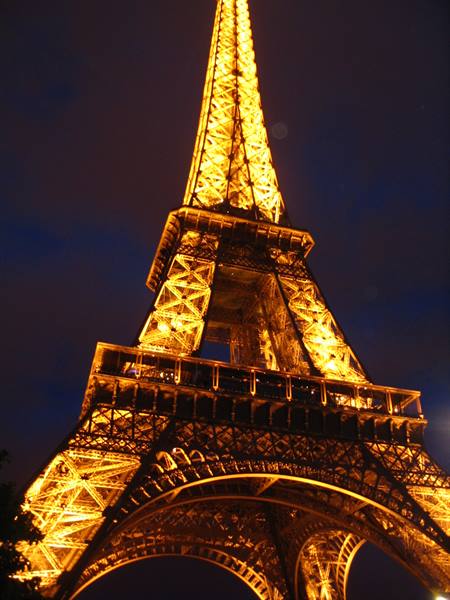 The Eiffel Tower glowing golden against the dark night sky in Paris