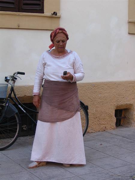 Woman in headscarf and long skirt beside a bicycle on the sidewalk