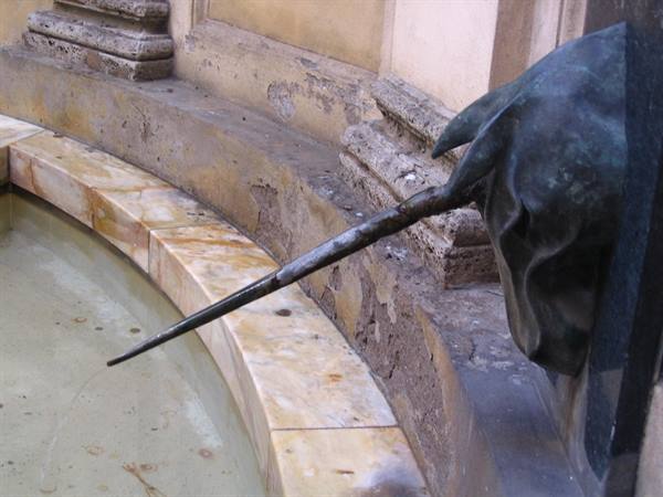 Bronze horse head spouting water into a marble fountain basin