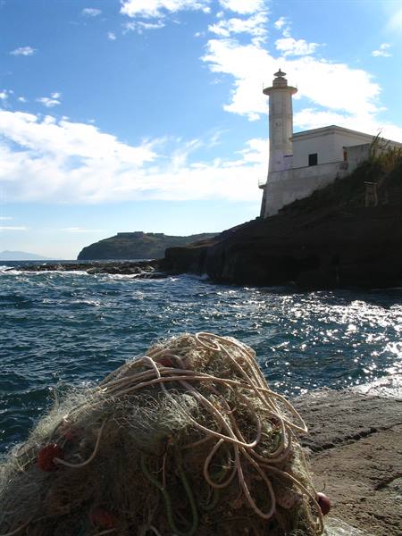 Fishing nets on rocks before the white Capo Miseno lighthouse