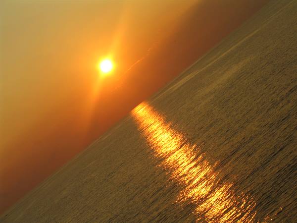 Low sun on the horizon, golden reflection on choppy sea water