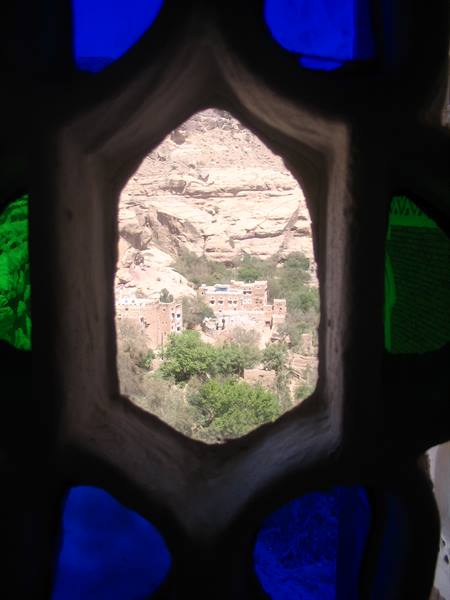 Brick village among trees seen through colored glass window, rocky canyon
