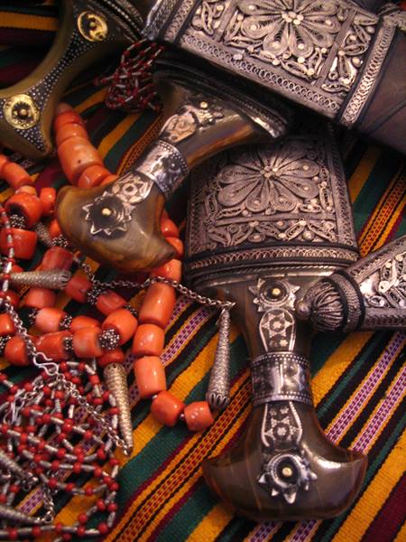 Curved daggers with silver filigree sheaths and orange coral bead necklaces