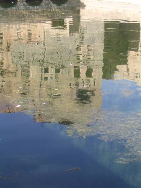 Reflection of an old building on blue-green canal water