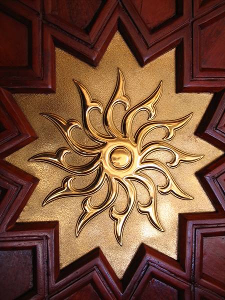 Golden sun carved on a red wooden star decoration
