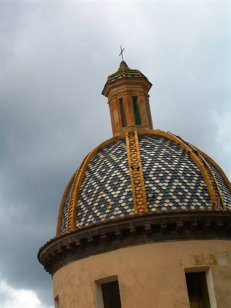 Dome decorated with blue and yellow tiles under cloudy sky