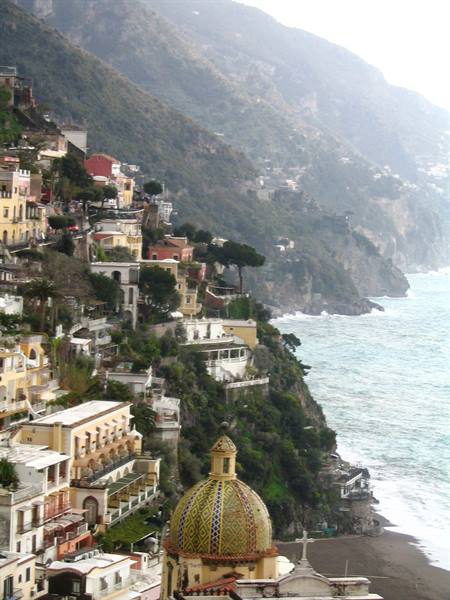 The majolica-tiled dome of Positano church above houses on the cliff