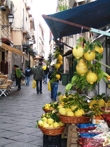 Baskets of lemons at a street market, people walking past stalls