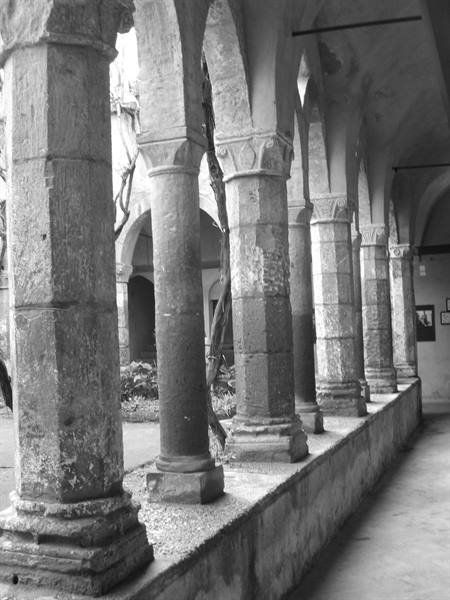 Stone columns with medieval arches in the cloister, natural light in black and white