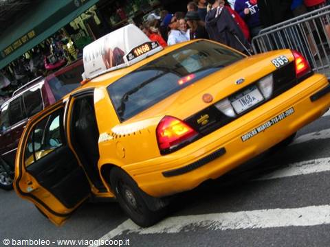 Yellow New York taxi with open door on a busy street