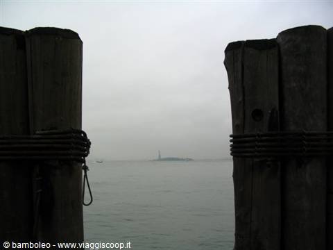 Statue of Liberty in the fog, seen between wooden posts wrapped with steel cables