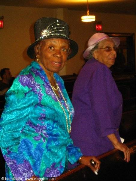 Two elderly ladies in elegant hats and pearls inside a church