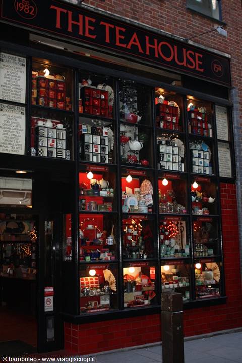 Illuminated Tea House shop window displaying teapots and tea boxes on red bricks