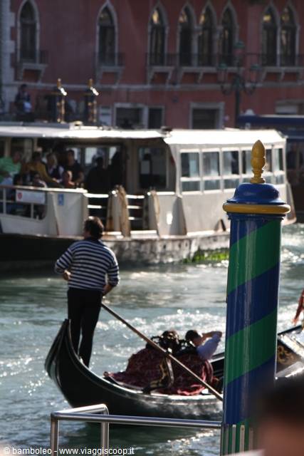 Gondolier rowing on Venice Grand Canal beside a vaporetto