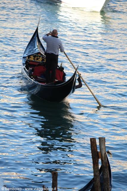 Striped-shirt gondolier rows a gondola on Venice water