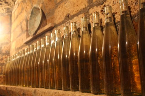 Glass bottles filled with wine aging in a stone cellar