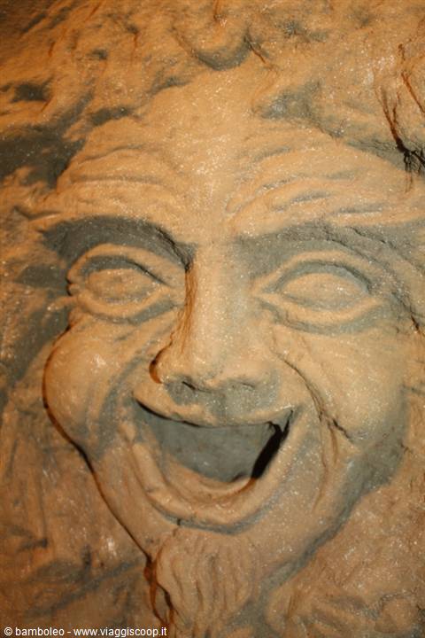 Face carved in rock, laughing mask with open mouth