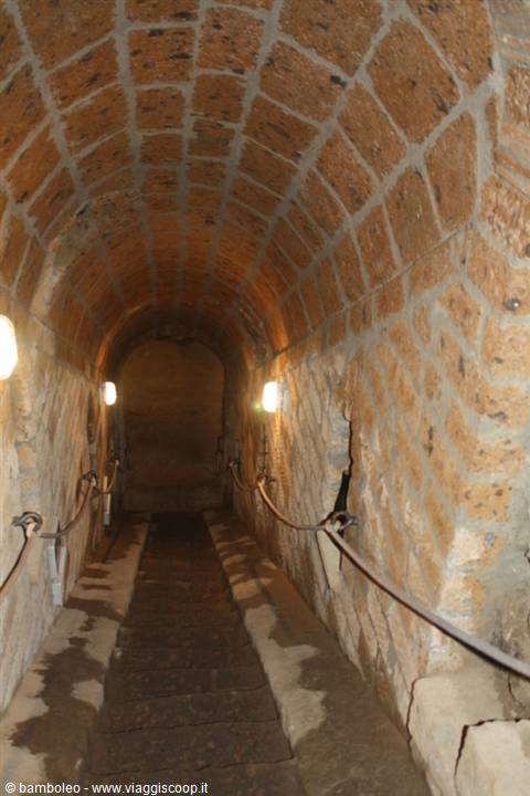 Stone-vaulted corridor with rope barriers and wall lights