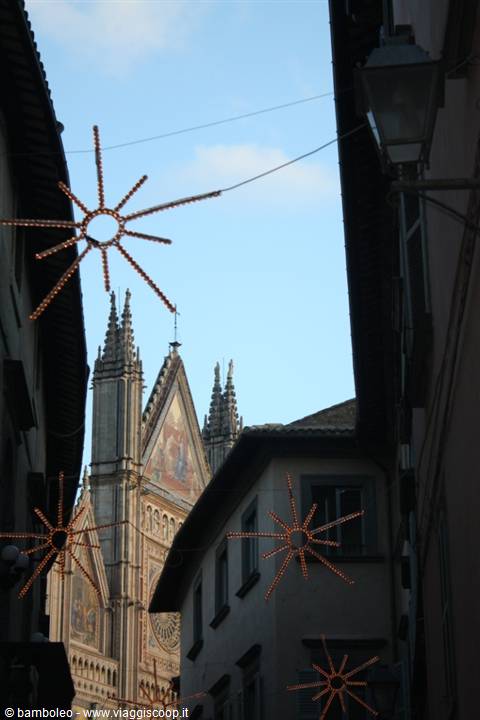 Orvieto Cathedral glimpsed between alleys with glowing Christmas star lights
