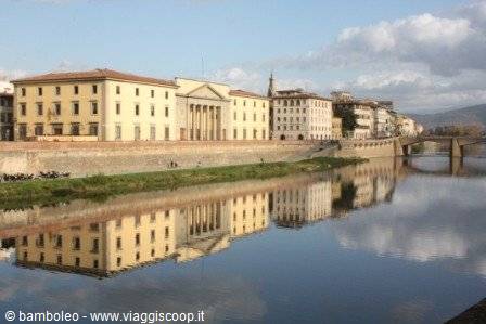 Historic palaces reflected in the Arno river in Florence, with bridge and hills