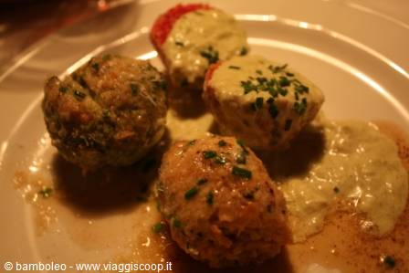 Irregular dumplings topped with green cream and chives, warm restaurant lighting