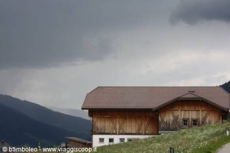 Wooden barn with red roof under storm clouds, alpine meadows