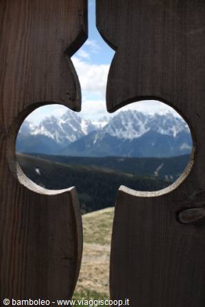 Snowy peaks framed through a heart-shaped cutout in wood