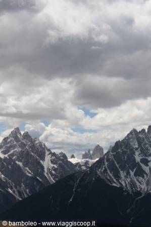 Snowy Dolomite peaks under grey clouds, Tre Cime di Lavaredo in the distance