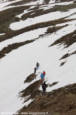 Group of hikers walking across snow and rocks on a mountain
