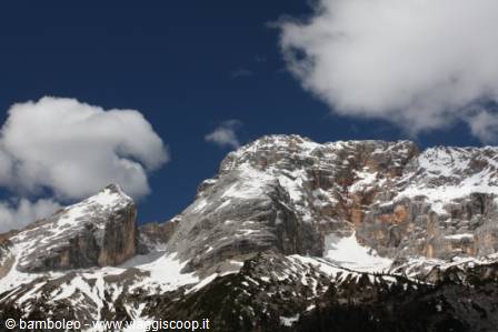 Rocky Dolomite peaks with snow patches, white clouds and blue sky