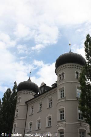 White castle facade with black dome towers under cloudy sky